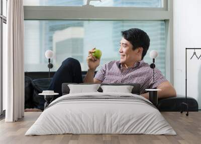 Healthy Asian man eating an apple. Wall mural