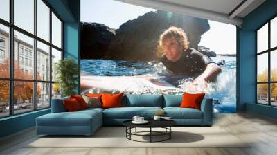 Man lying on surfboard in the water Wall mural