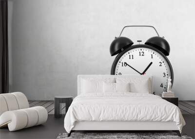 A black alarm clock is on the wooden floor. Concrete wall. Wall mural