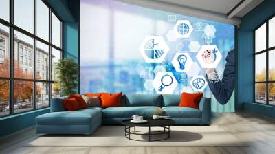 A businessman's hand in formal suit is drawing a business target icon on the glass screen. Modern panoramic office is on the background. Wall mural