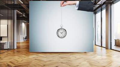 A hand holds a pocket watch in a chain. Light blue background. Time is money concept. Wall mural