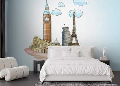 A man's hand holds sketches of the most famous places in Italy, Great Britain and France. The concept of tourism and sightseeing. Light blue background. Wall mural