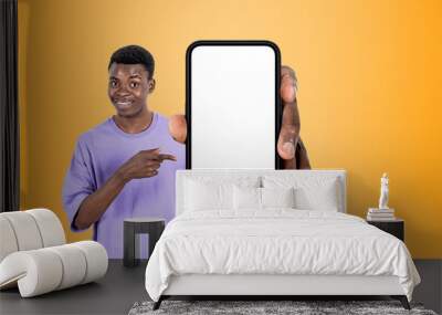 African man pointing at phone mockup display, yellow background Wall mural