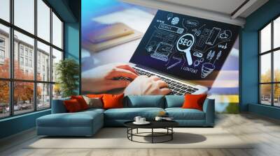 Businessman hands working on laptop at office workspace to discover search engine optimization to succeed in start up. SEO icons sketch on glass screen. Wall mural