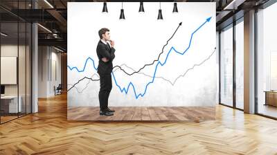 Thoughtful businessman in room with growing graphs Wall mural