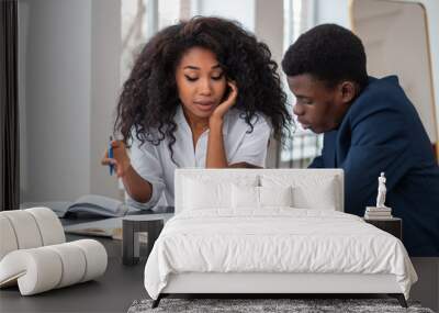 Two african business people brainstorming, looking at papers on desk Wall mural