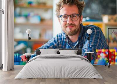 A man in glasses smiles as he leans over a table covered in bright plastic building blocks Wall mural