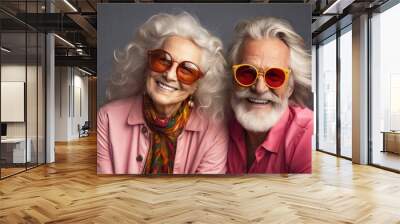 Elderly couple with sunglasses smiling, gray background. Wall mural