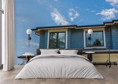 The top of the house with nice windows on cloudy sky background Wall mural