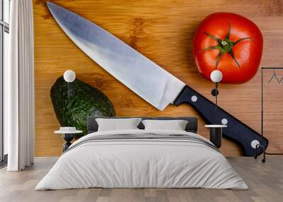 A Tomato and an Avocado on a cutting board with a Chef's knife. Wall mural