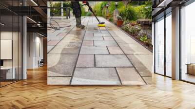 Cleaning stone slabs on patio with the high-pressure cleaner. Person worker in rubber boots cleaning the outdoors floor. Wall mural