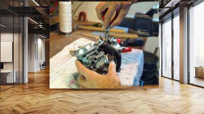 motorcycle carburetor. Automotive Carburetor Repair. Male Using A tong To Rebuild A Carburetor On A Workbench. Mechanic man checking carburetor of motorcycle. Repair. Maintenance and fixing concept.   Wall mural