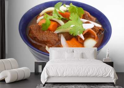 beef stew and vegetables in blue bowl on white background Wall mural