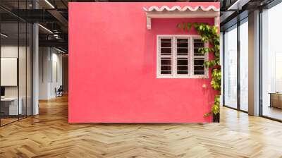 A colorful pink wall of caribbean house with window space and flower and plants and colonial roof. Wall mural