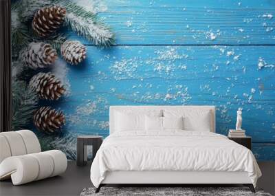 winter holiday scene with pine branches, pinecones, and snow on a blue wood backdrop Wall mural