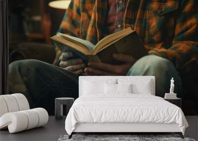 A man is reading a book while sitting on a couch Wall mural