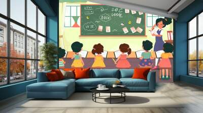 Woman teacher at chalkboard in classroom. Elementary school children studying in class room. Wall mural