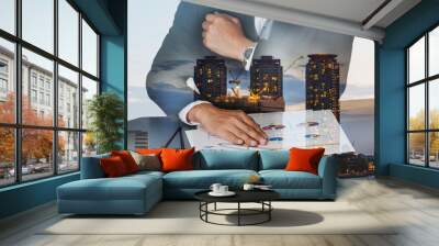 Businessman hand put on the chart document, construction crane and building in the evening, twilight as business, meeting, analysis and industrial concept. Wall mural