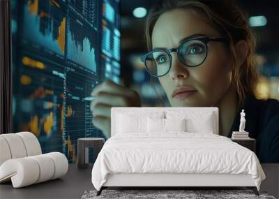 A businesswoman in glasses intently reviews complex financial charts and graphs on a screen in a sleek office environment. The lighting adds a sophisticated ambiance Wall mural