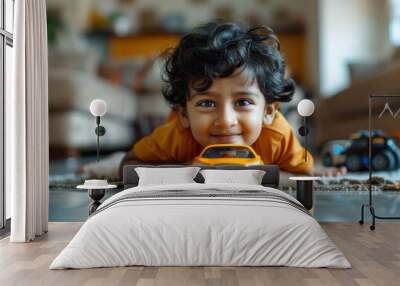 A cheerful young boy plays with a toy car, lying on the floor at home, enjoying his time in a bright and cozy environment Wall mural