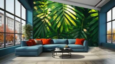 A close-up of vibrant green palm leaves illuminated by sunlight, creating a lush and tropical backdrop Wall mural