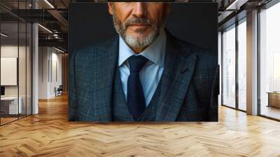 A man in a suit and tie is standing in front of a black background. He has a serious expression on his face Wall mural