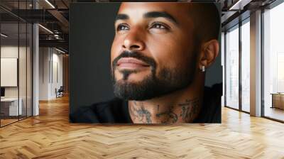 A man with a beard and a tattoo on his neck is looking at the camera. He has a serious expression on his face Wall mural