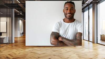 A man with a white shirt and tattoos on his arms is smiling and posing for a picture. Concept of confidence and self-assurance, as the man is proud of his appearance and is comfortable in his own skin Wall mural