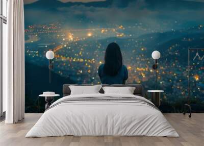 A woman is seated on top of a hill, gazing at a cityscape below her Wall mural