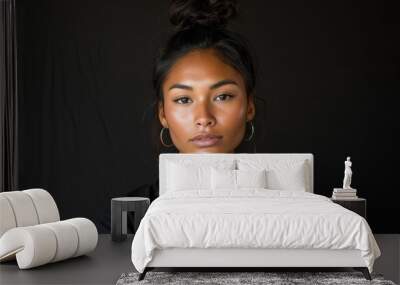 A woman with a bun on her head and a black shirt. She has a tan face and is wearing earrings Wall mural