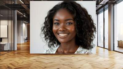 A woman with curly hair and a white shirt is smiling. She has a bright, happy expression on her face Wall mural