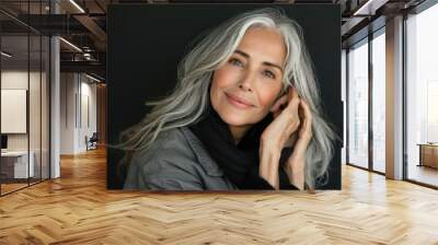 A woman with long gray hair is smiling and wearing a gray jacket and black scarf. She is posing for a picture Wall mural