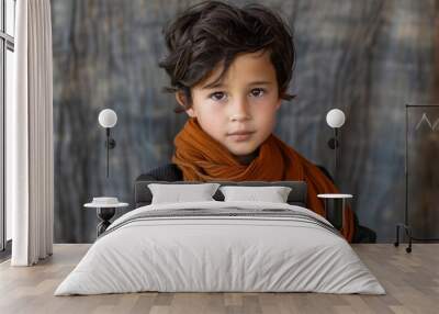 A young boy with short hair wrapped in an orange scarf looking at the camera Wall mural