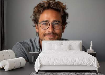 A young man with stylish hair and glasses smiles warmly, showcasing confidence and approachability in a bright indoor space Wall mural