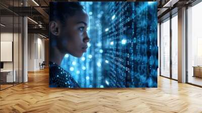 A young woman stares intently at a screen filled with lines of code, illuminated by a blue glow Wall mural