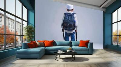 Isolation of a young arab gulf boy carrying a backpack viewed from behind on a white background Wall mural