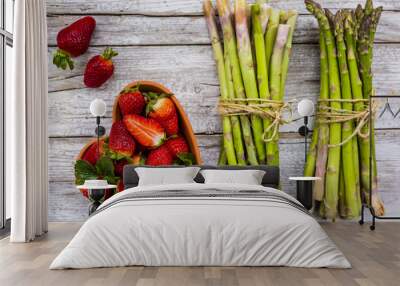 Fresh strawberries and raw green asparagus on a wooden background.  Wall mural