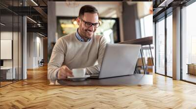 Businessman working on a laptop computer and drinking coffee Wall mural