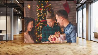 Mother and father giving Christmas present to their son Wall mural