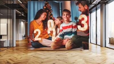 Parents and children holding illuminative numbers 2023 while celebrating New Year Wall mural