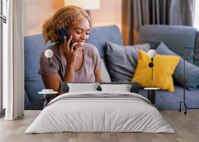 Woman speaking on the phone while relaxing at home Wall mural