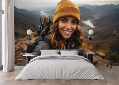 Woman taking a selfie at mountain viewpoint while mountaineering Wall mural