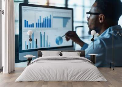 Businessman is analyzing data on a computer screen, focusing on charts and graphs. Wall mural