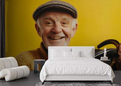 Elderly man smiling while holding the steering wheel, set against a yellow background, symbolizing active senior life   - Wall mural