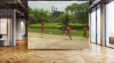 Surabaya, Indonesia - 14-01-2023 : Children playing a soccer in the paved field. They look so happy. Wall mural