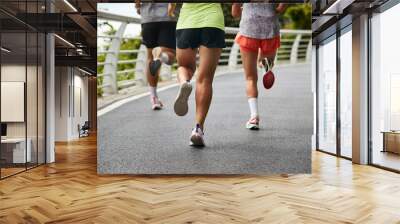 close-up shot of legs and feet of group of young asian adults people running jogging outdoors Wall mural