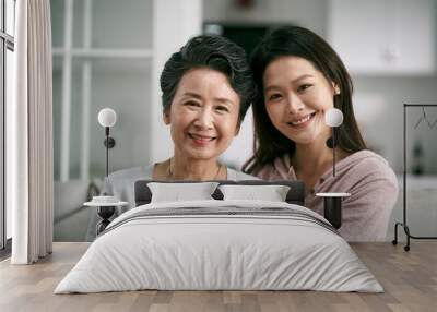 portrait of asian senior mother and adult daughter looking at camera smiling Wall mural