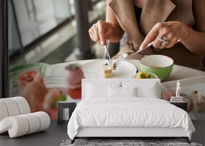 woman eating dessert using fork and knife in restaurant Wall mural