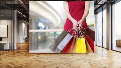 young woman standing walking with shopping bags in hands Wall mural