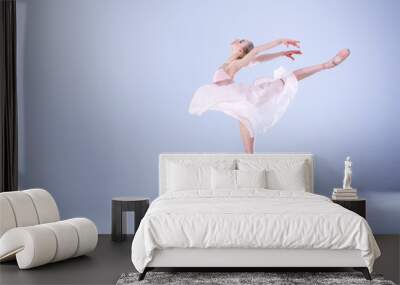 Ballet Perfection. Young and beautiful ballerina is dancing in a white studio full of light. Wall mural